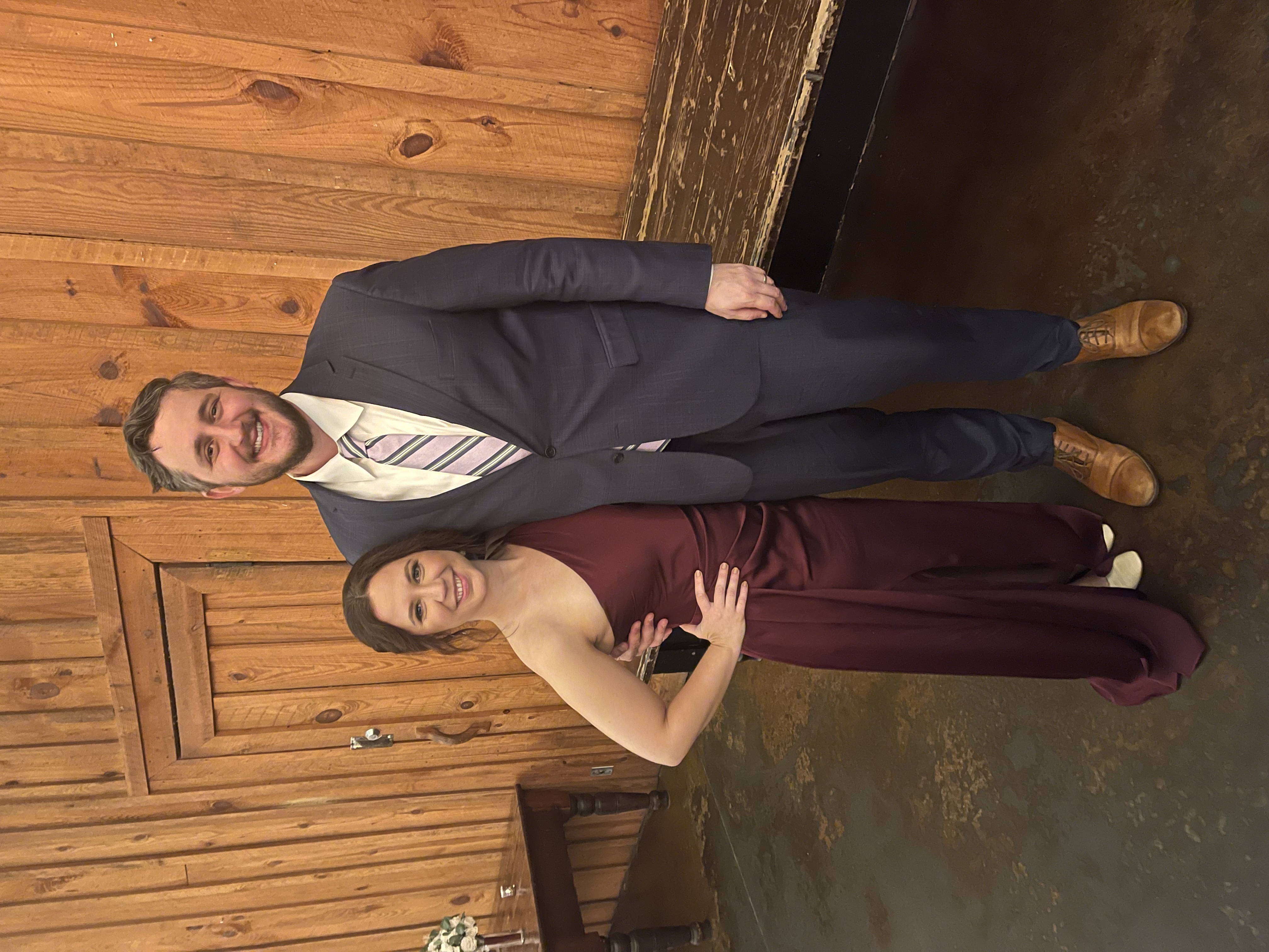 Peter and his wife, Katie Eck, standing together next to a fireplace with Christmas ornaments and a Christmas tree in the background.